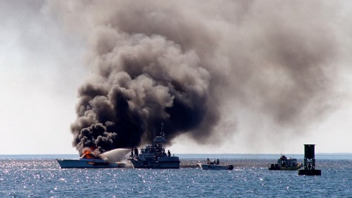 Boat burns off Menemsha as CG pours water on flames.