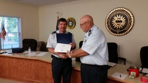 Doc Deiss, facing camera at left, shakes hands with Fran Doyle as they both hold the certificate