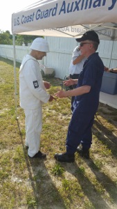 John Craig, standing at left and wearing a white Life-Saving uniform, chats with Bruce White, wearing the ODU uniform. The front edge of the canopy, which partially reads "U.S. Coast Guard Auxiliary," is just above their heads.