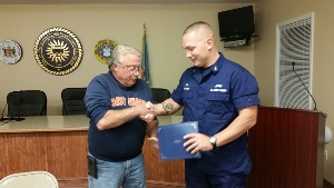 Jay, at left, shakes hands with Chief Holcomb, who holds the award certificate