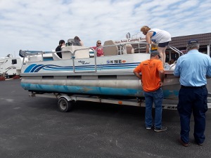 Ralph Carotenuto, standing at right, discusses the examination process with the trailered pontoon owner as familiy members wait on board