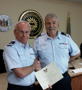 John Craig, standing at left, shakes hands with Ralph Carotenuto as he holds his certificate