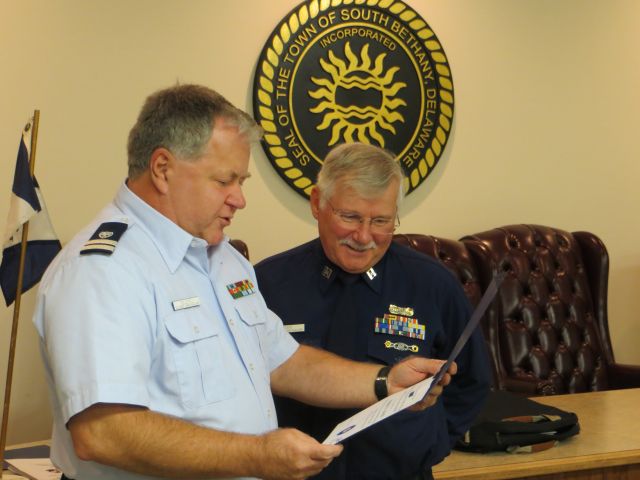 Bob Adams, standing at right wearing Winter Dress Blue, reads on as Mike Geletej, in Trops, reads the Patrol Specialty certficate