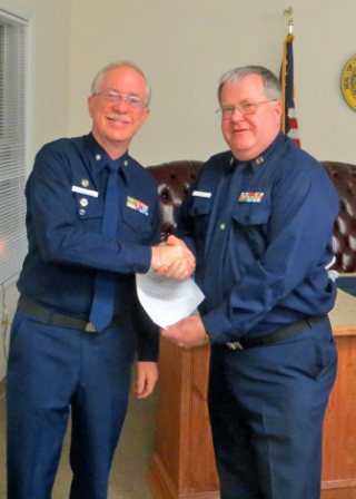 Bruce White, facing camera at left, shakes hands with Mike Geletej as Mike holds his written orders for 2013. Both are wearing Winter Dress Blue uniform.