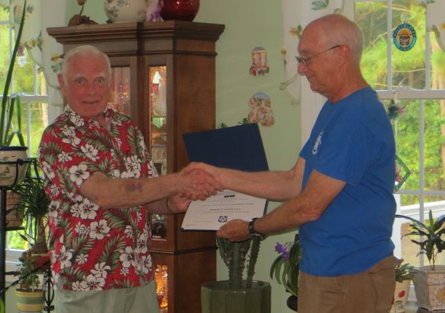 Bob Lesperance, standing at left, shakes hands with Joe Harris while receiving his citation