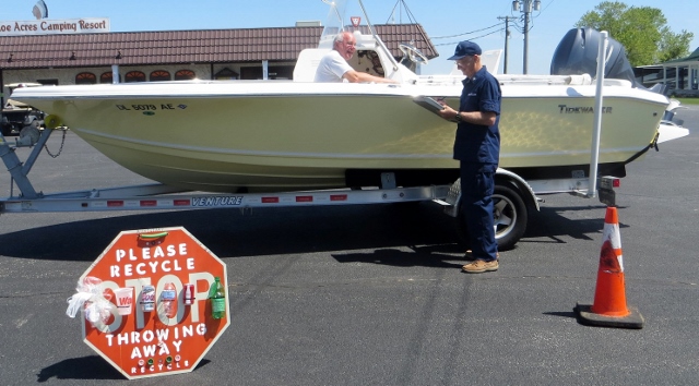 Joe Harris (in ODU) holds his clipboard as he conducts a VSC on a trailered boat as the owner looks on