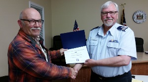 Barry Widmer, standing at left, holds his Service Award with his left hand while shaking hands with Steve Straneva, who also holds the certificate