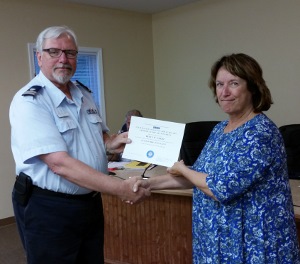 Steve Straneva, standing at left, shakes hands with Betty Smith as they bold hold the edges of the certificate