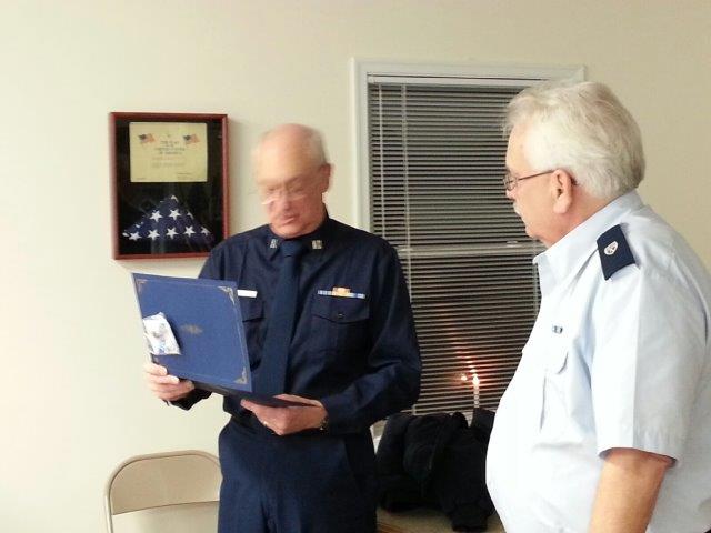 Joe Harris, at left in Winter Dress Blue, reads the FSO certificate as Dennis Burgard, iin Trops, looks on