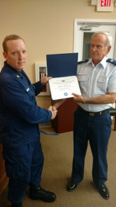 BM2 Raxter, in ODU at left, shakes hands with John Craig while both hold his Program Visitor certificate