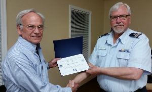 John Craig, standing at left, holds his membership certificate with his left hand while shaking hands with Steve Straneva, who also holds the certificate
