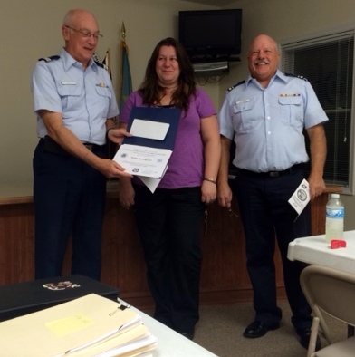 Joe Harris, facing the camera at left, holds open the membership certificate, as Dawn Curlett stands in the middle with Dave Ritondo to her left. (Joe and Dave wear the Tropical Blue uniform.)