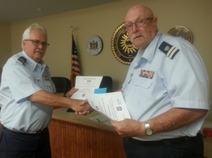 Dennis Burgard, standing at left, shakes hands with Fran Doyle, while holding his certificate in his left hand