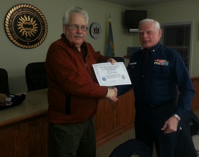 Denny Burgard (standing at left, in civilian clothes) shakes hands with Bob Lesperance (Winter Dress Blue uniform) while holding his "Century Club Award" certificate.