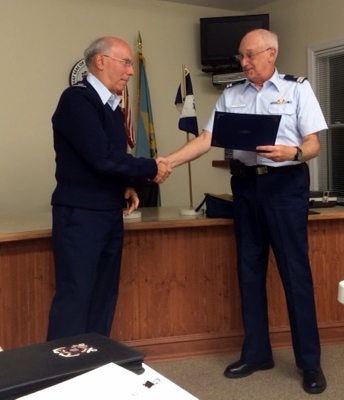 Fred Zikas, at left, shakes hands with Joe Harris after Joe reads his certificate. Both wear Tropical Blue uniforms and Fred also wears a wooly-pully.