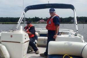 Fran Doyle, seated at the helm of the pontoon, and Bob Adams, standing at right, face forward as they leave Vines Creek Marina