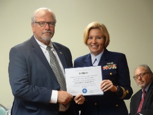 Steve, in business suit at left, receives a certificate from a Coast Guard officer