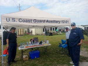 Joe Harris stands at the left front corner of the "U.S. Coast Guard Auxiliary 12-01" canopy and Bob Lesperance and Fran Doyle stand at the right corner