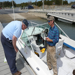 Vessel Examiner Bill Tower affixes the Safety Check sticker to a boat which just passed inspection.