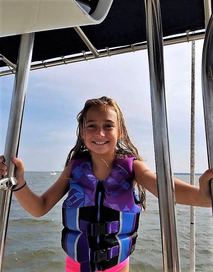 Photo of girl on boat wearing her PFD.