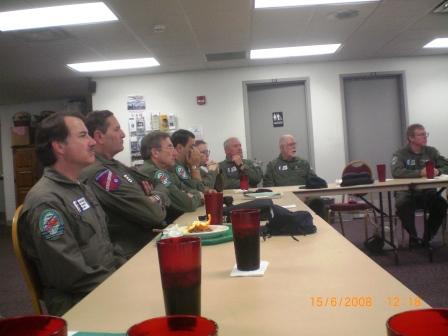 Group of men in Green Aviaitor suits sitting around a table at a meeting for Aviators 