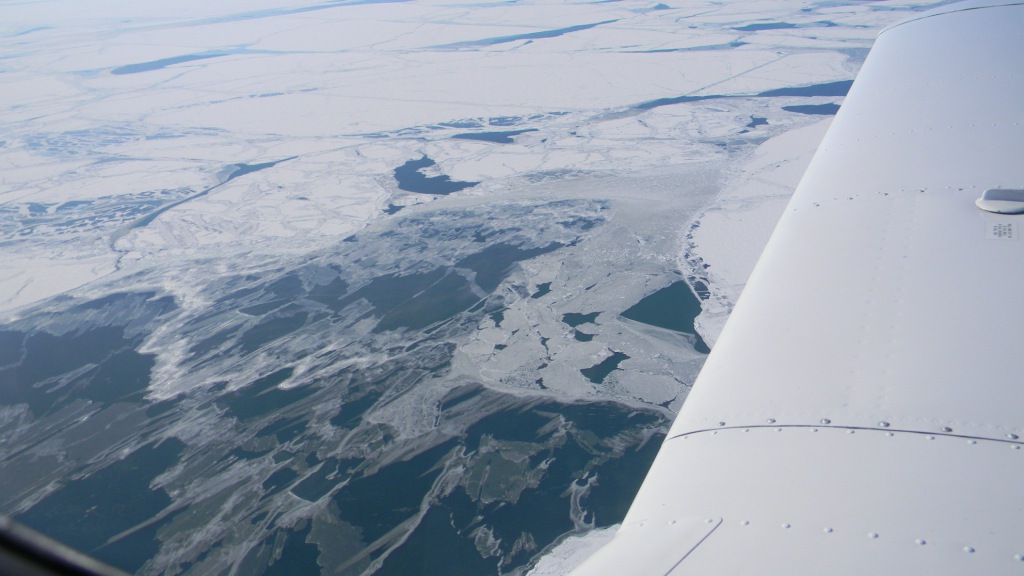 Shot from a plane with a portion of the wing in the  foreground.  Below you see an ice blocked river 