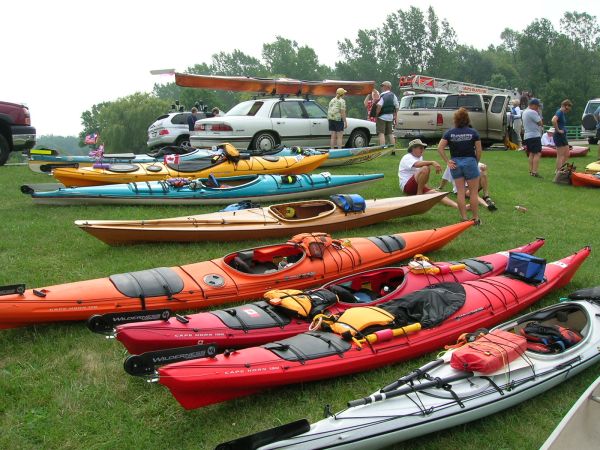 Picture of multiple kayaks, on the grass, ready for use.