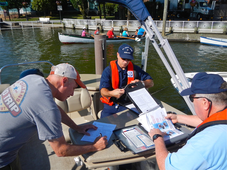 A boat owner signs a Vessel Safety Check form with members of flotilla 2 5 O 8