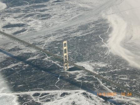 Picture of a large Bridge (Mackinac Bridge) taken from the Air. The lake underneath is ice covered 