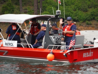 Picture of an Auxiliarist in uniform at the stern of a jetboat with several fellow Auxiliarists forward