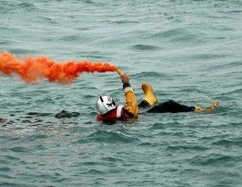 Picture of a person in the water holding a flare with orange smoke