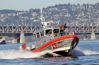 Picture of a Coast Guard patrol boat with a uniformed Coast Guardsman manning a gun