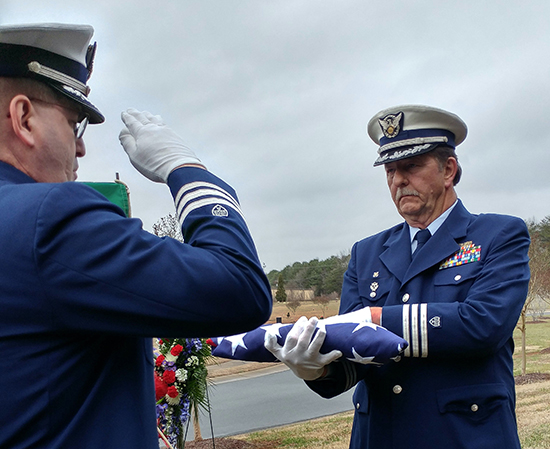 Auxiliarts salutes American flag being held by another auxiliarist